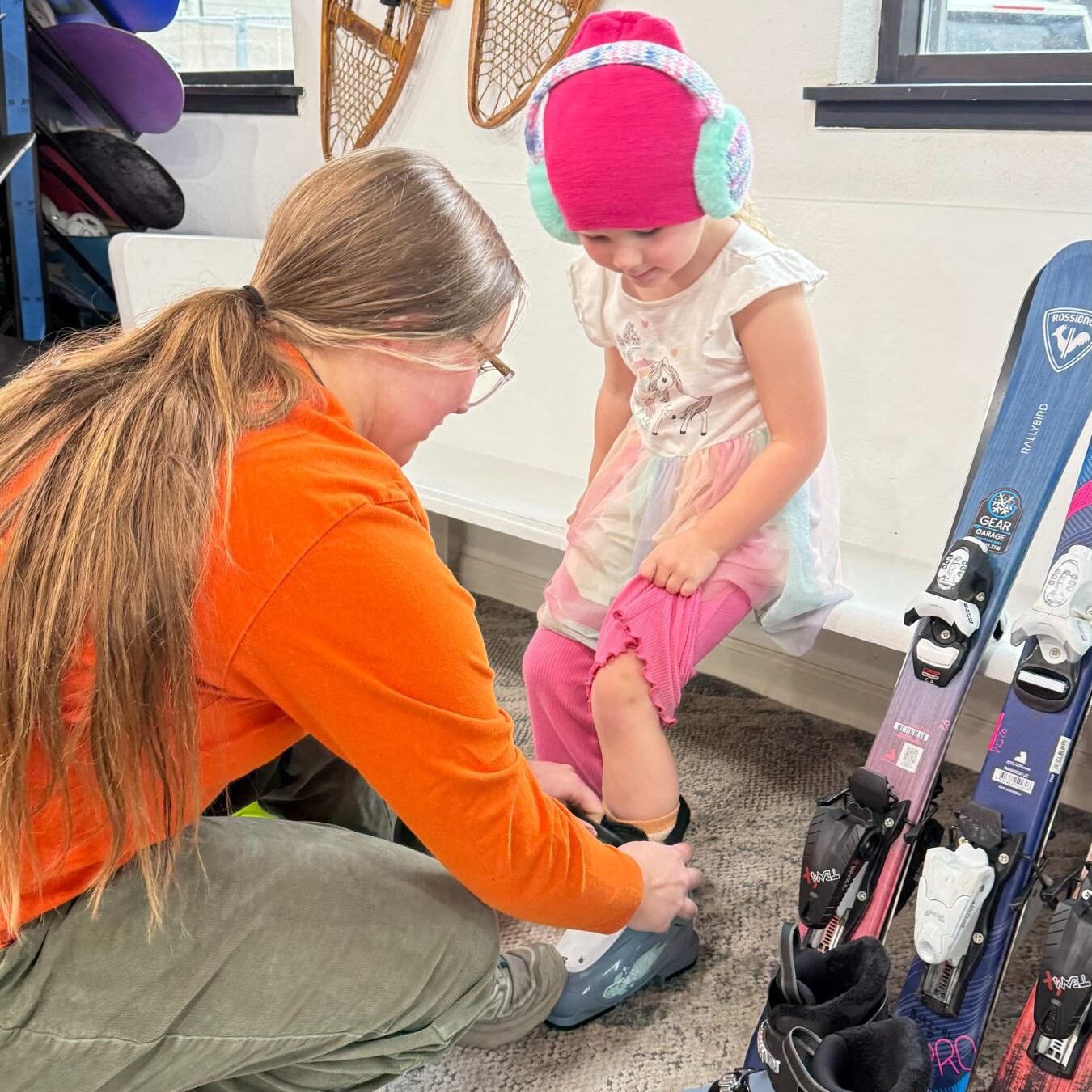 Expert staff fitting child with ski boots at Gear Garage seasonal rental shop